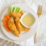 round plate with panko breaded chicken tenders and carrots and celery and honey mustard