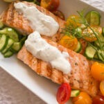grilled salmon with dill sauce, cherry tomatoes, and cucumbers